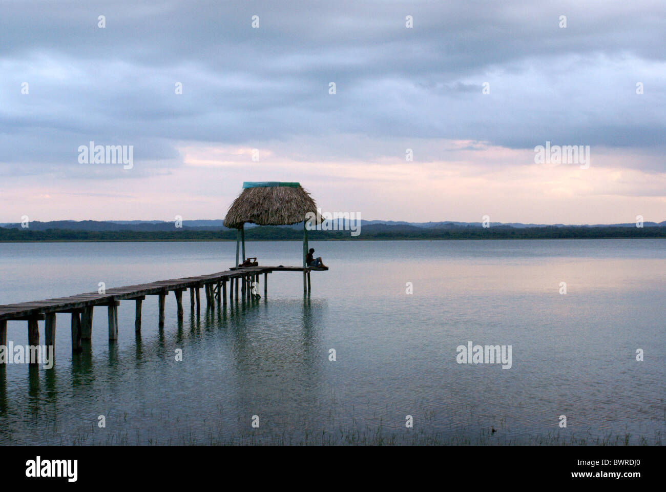 Personne assise sur une jetée en bois sur le lac Peten Itza près de Santa Elena, El Petén, Guatemala Banque D'Images