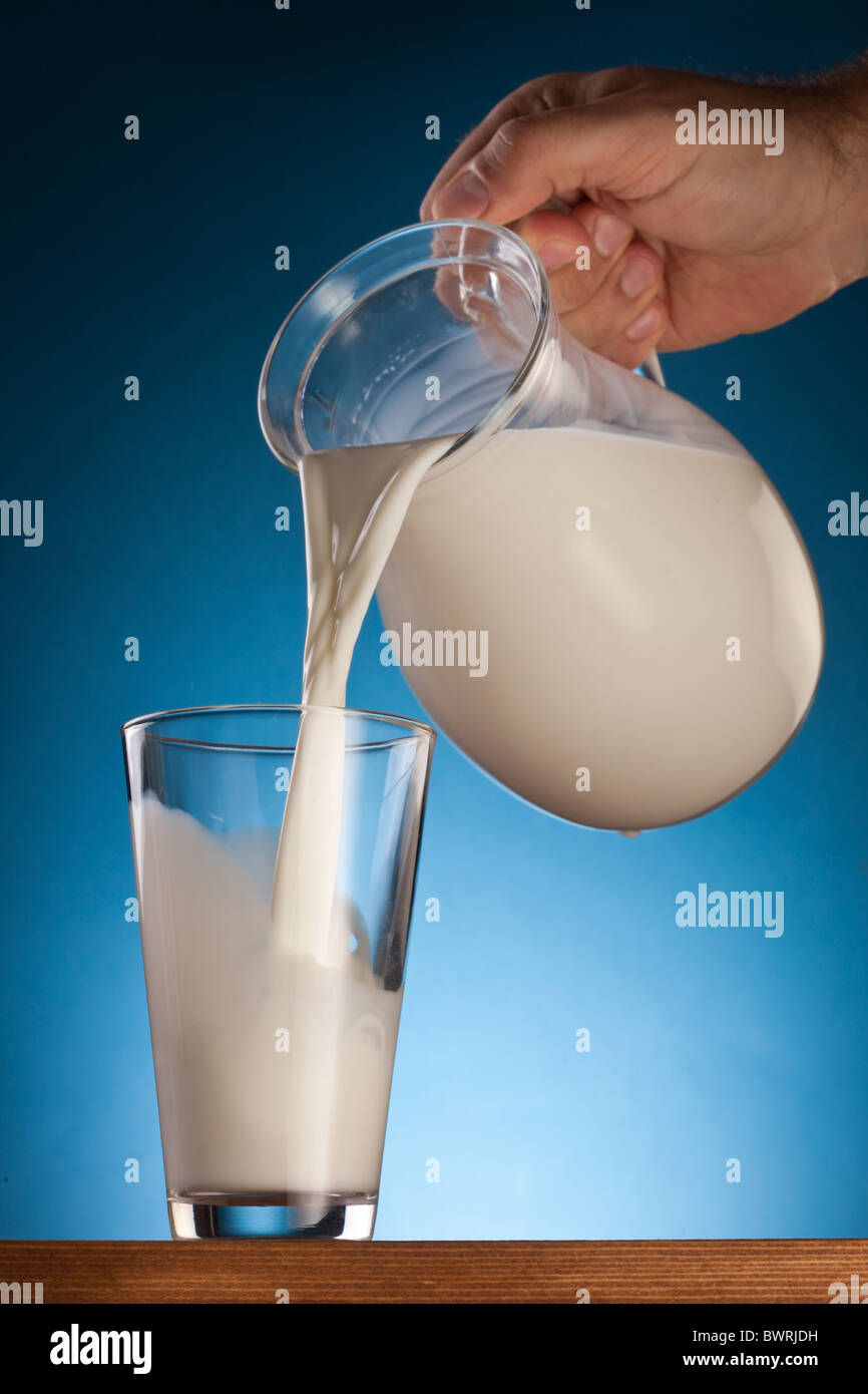 Le verre et le pot de lait sur un fond bleu. Banque D'Images