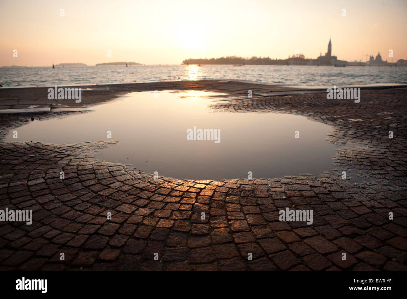 Une flaque à gauche de l'inondation du lagon à marée haute dans l'incandescence du soir à Venise. Banque D'Images