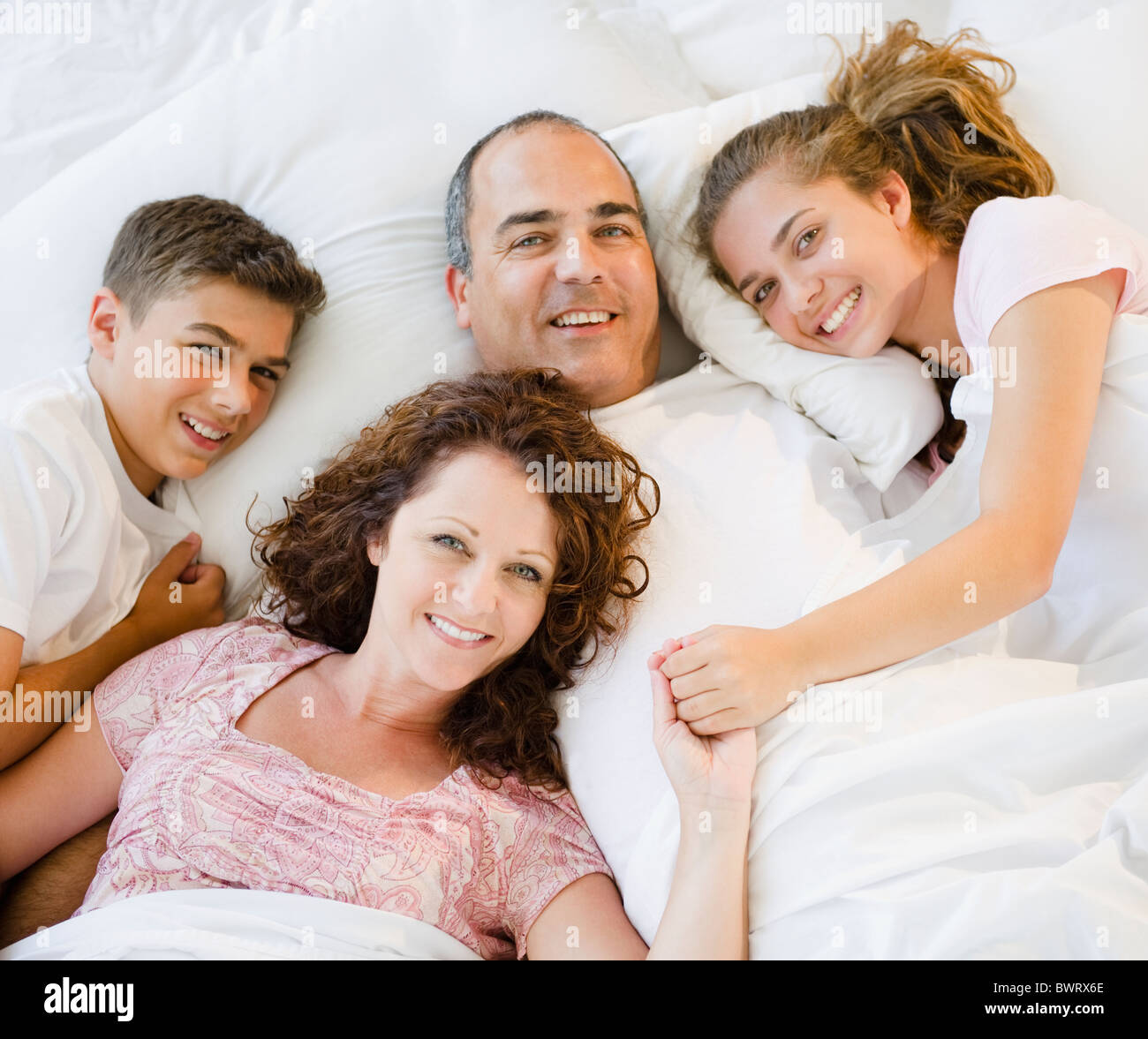 Smiling Hispanic family fixant ensemble au lit Banque D'Images