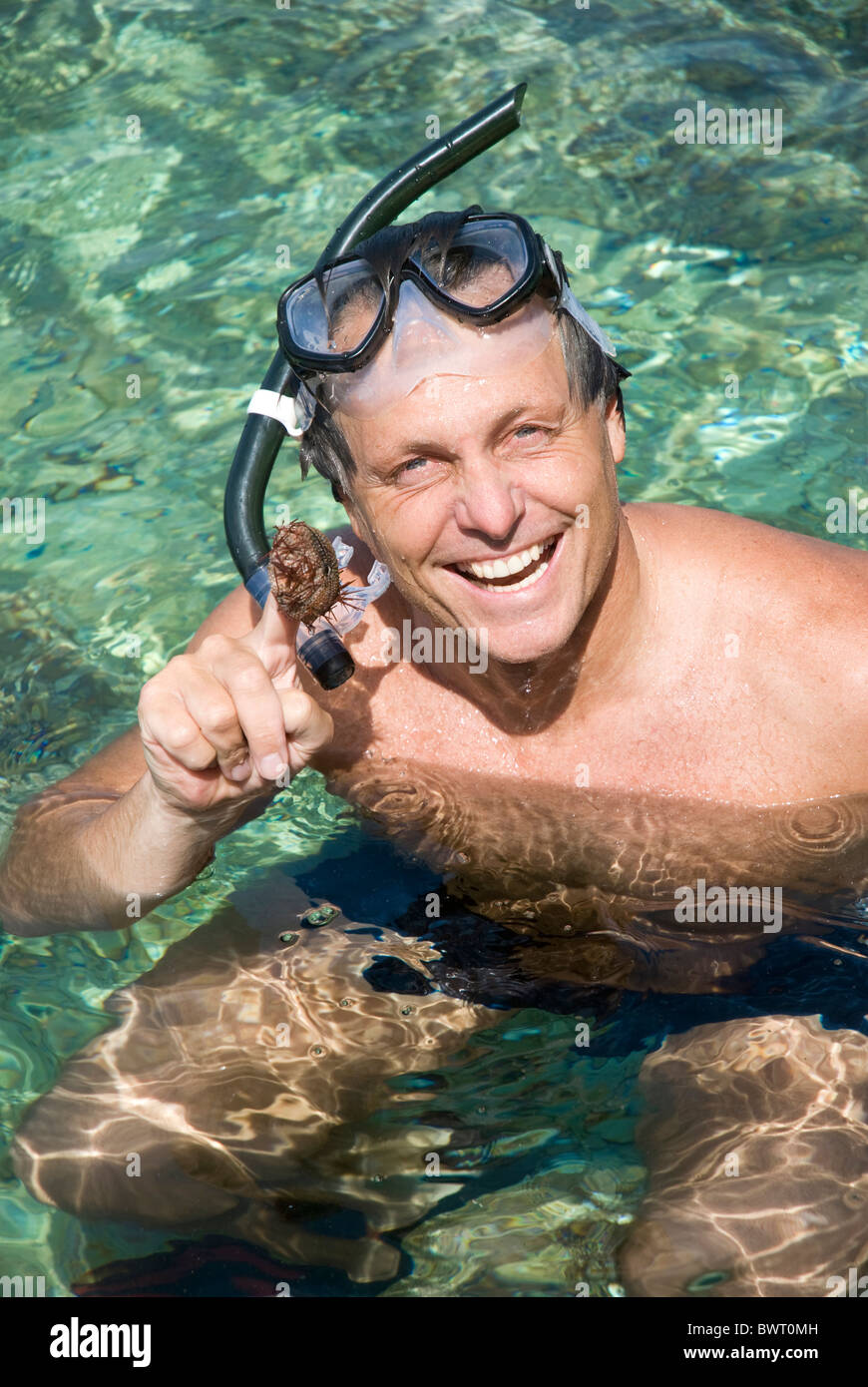 Une happy smiling young man holding un oursin après la plongée dans la belle mer bleue de la Grèce. Banque D'Images