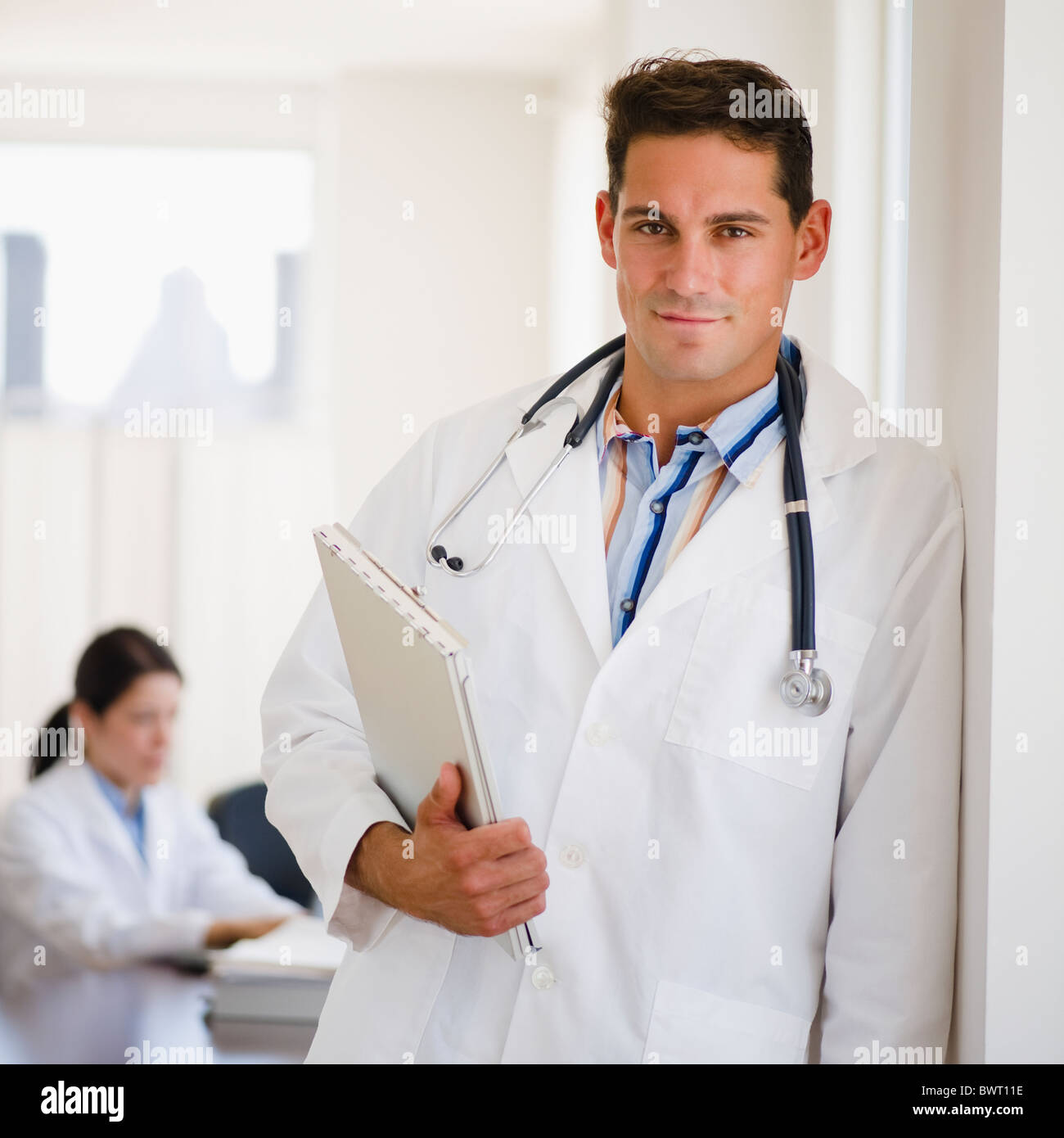 Mixed Race doctor holding medical record dans le cabinet du médecin Banque D'Images Mixed Race doctor holding medical record dans le cabinet du médecin Banque D'Images