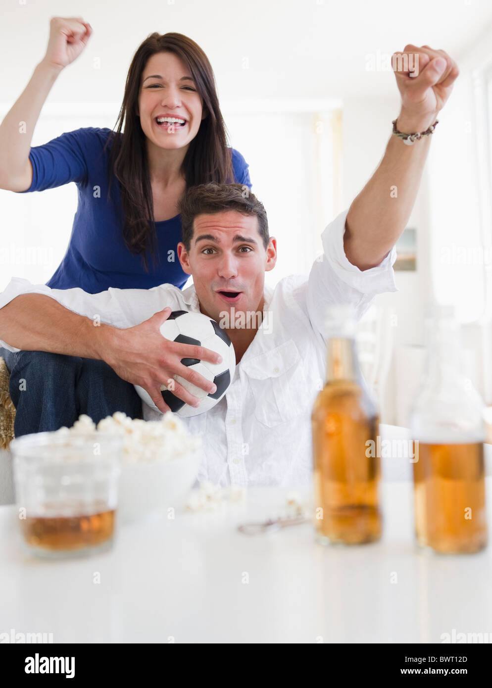 Mixed Race couple en train de boire une bière et se réjouissant de match de foot Banque D'Images