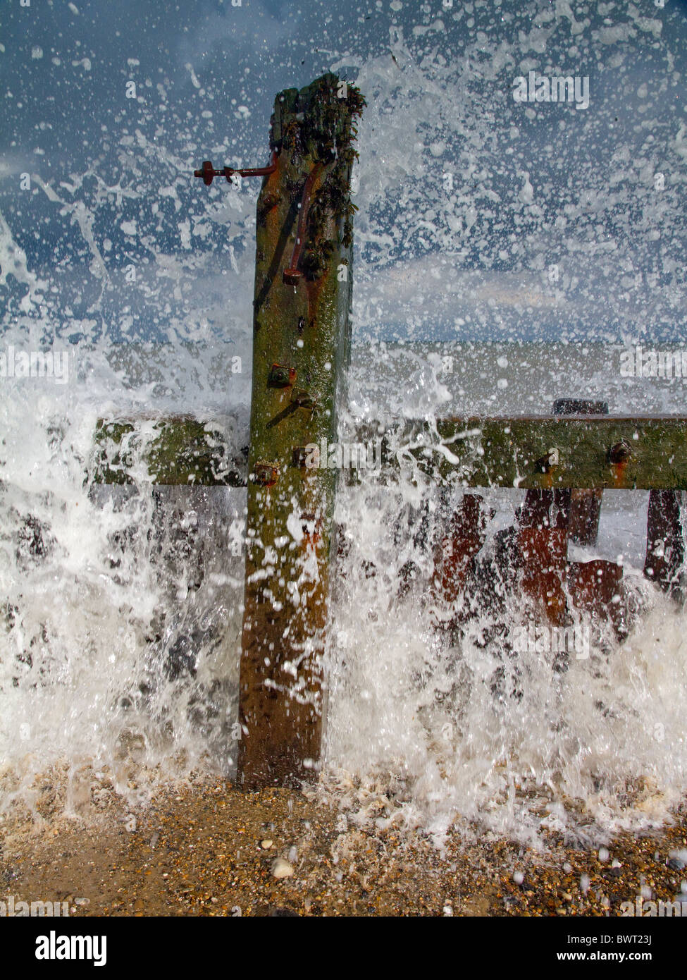 Mouches de pulvérisation après une vague hits abandonné sur les défenses maritimes Happisburgh beach Banque D'Images