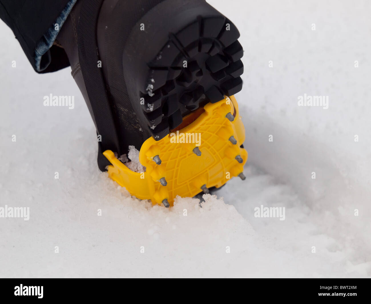 Le pied de femme dans un démarrage marche montrant crampon montés pour la sécurité sur la glace et la neige glissante Banque D'Images