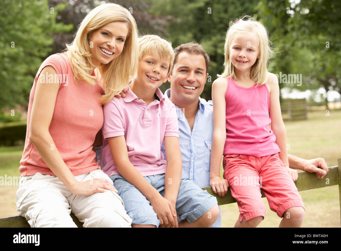 Portrait Of Family Sitting on Fence in Countryside Banque D'Images