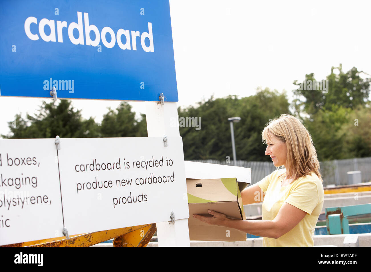 Woman at Recycling Centre Disposing of Cardboard Banque D'Images