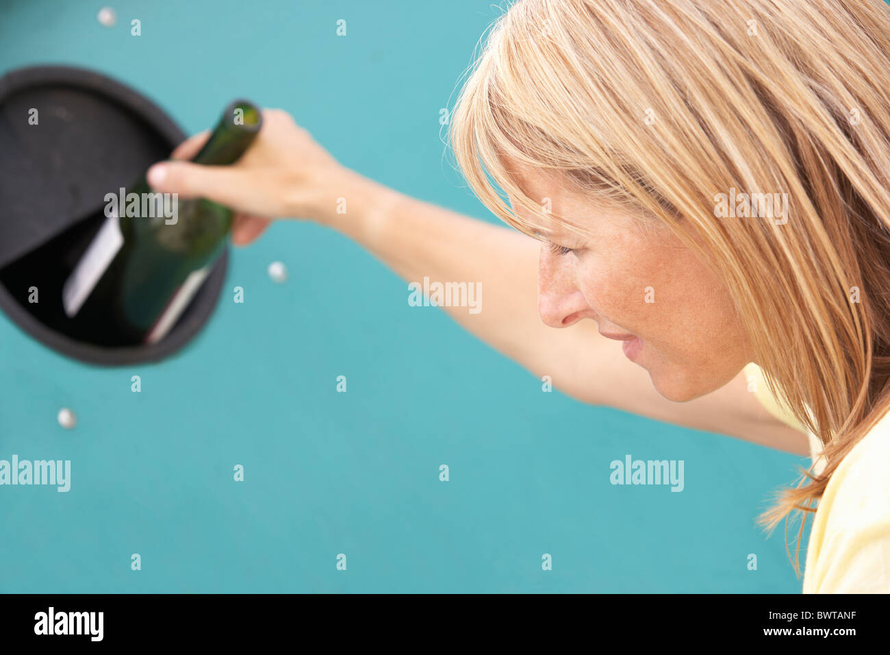 Woman at Recycling Centre Disposing of Glass At Bottle Bank Banque D'Images