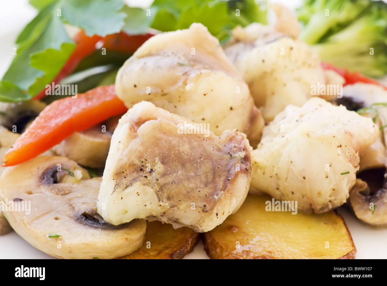 Diable la mer avec des frites, champignons, le paprika et le brocoli comme gros plan sur une plaque blanche Banque D'Images