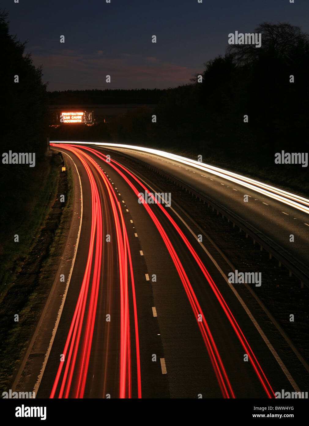 Light Trails de mouvement du trafic prises d'en haut à deux voies avec un panneau à message variable dans la distance. Banque D'Images