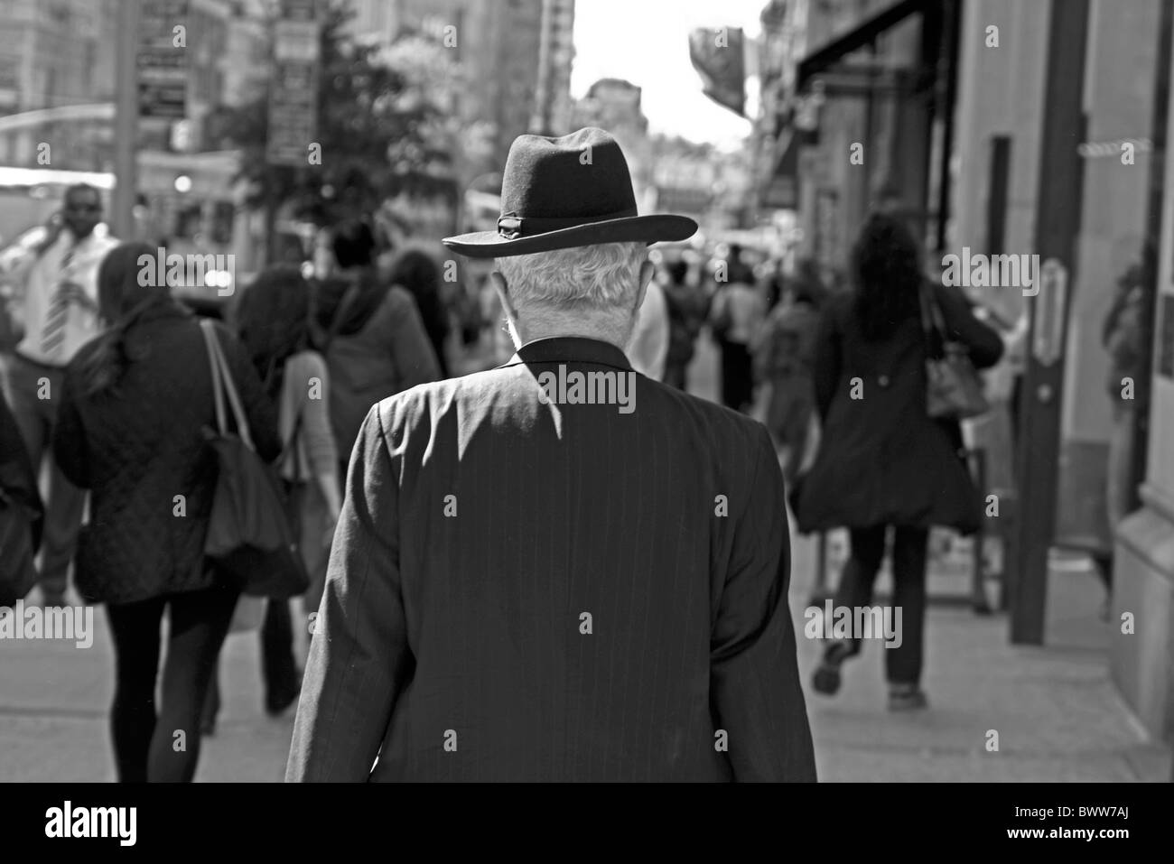 Un homme qui marche dans la ville de New York se distingue dans l'isolement de l'animation qui se passe autour de lui. Banque D'Images