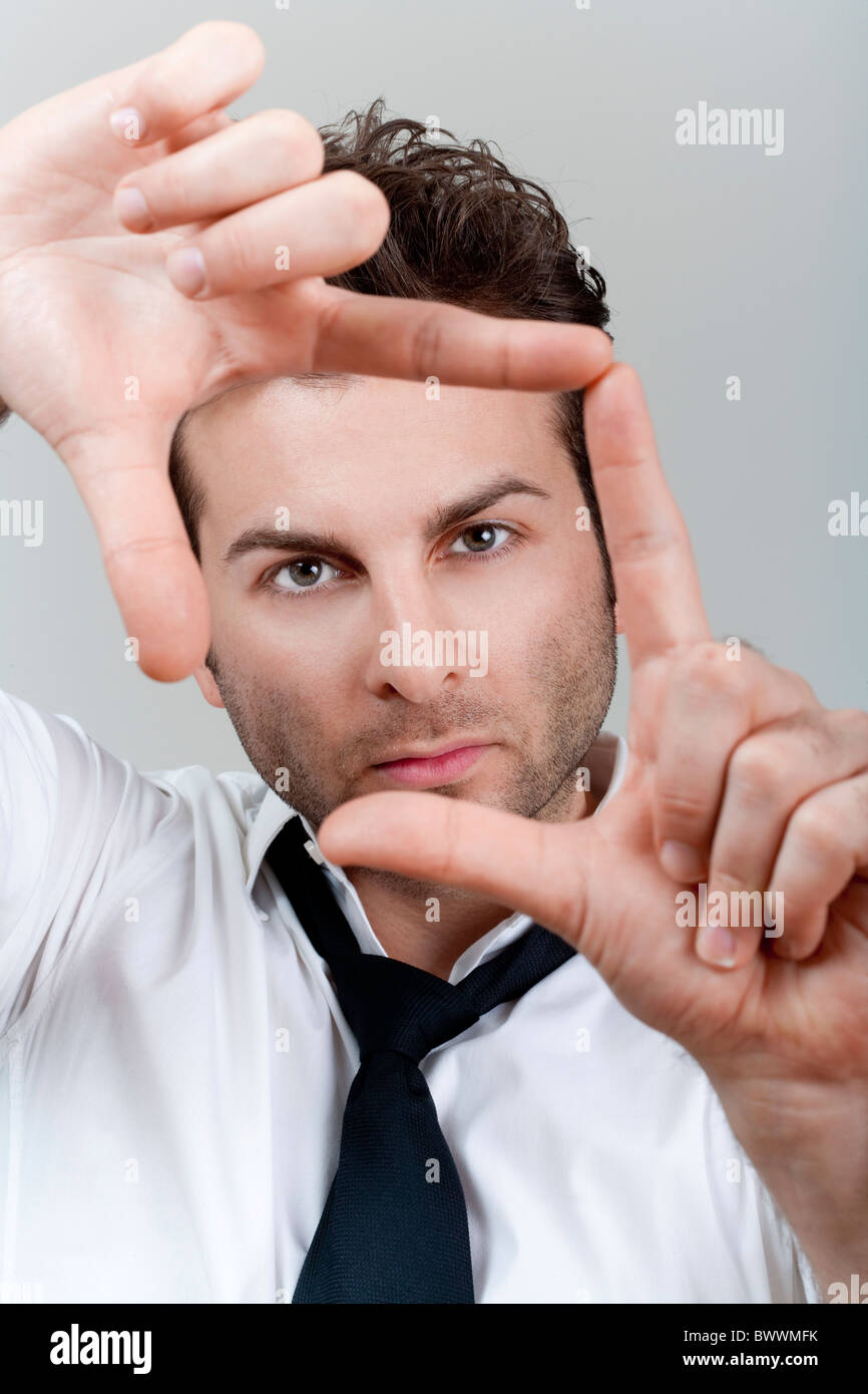 Homme d'affaires en chemise blanche et cravate formant cadre avec ses doigts l'accent Banque D'Images