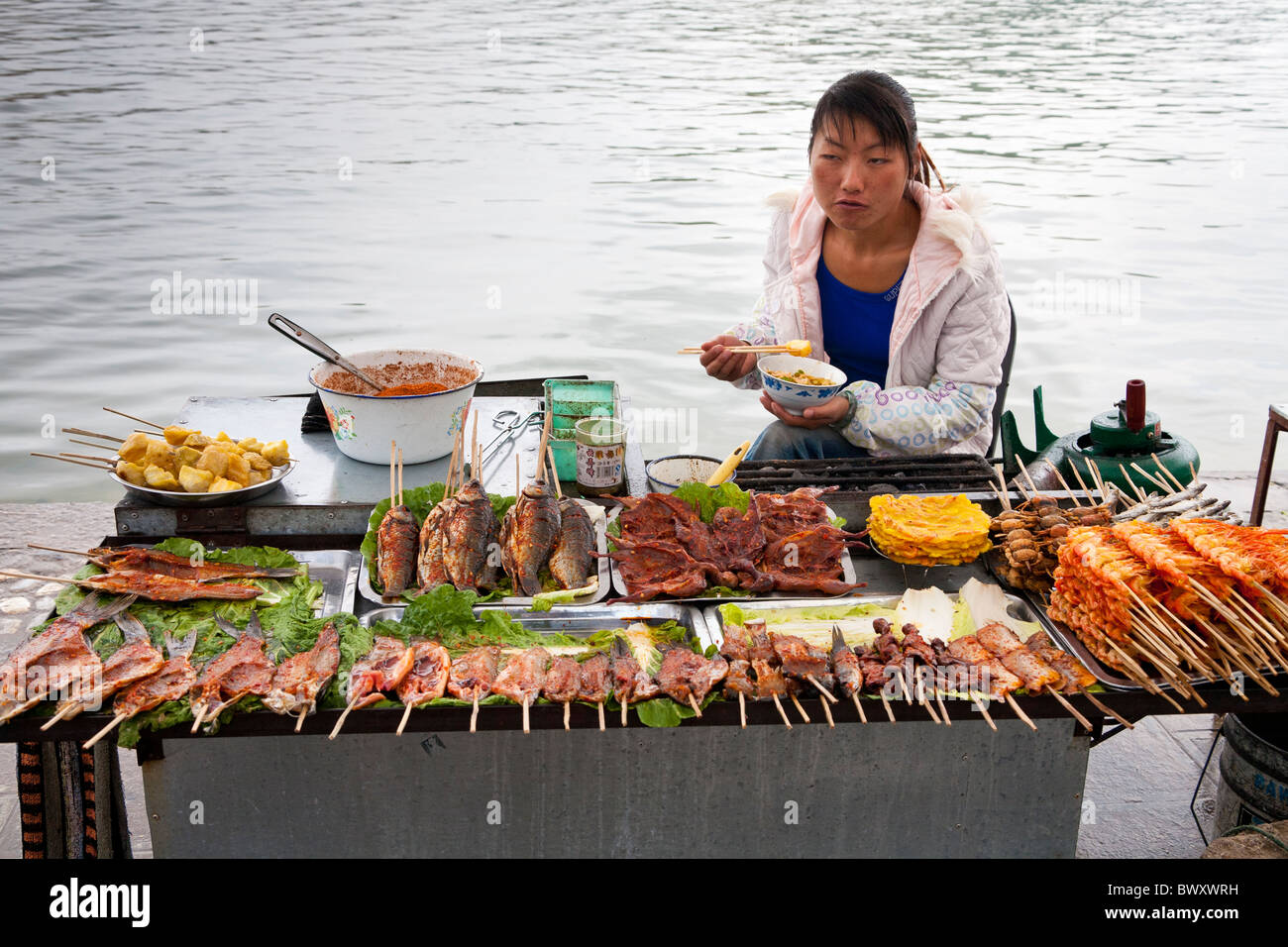 Femme vendant des aliments cuits, Île Jinsuo, près de Dali, Yunnan Province, China Banque D'Images