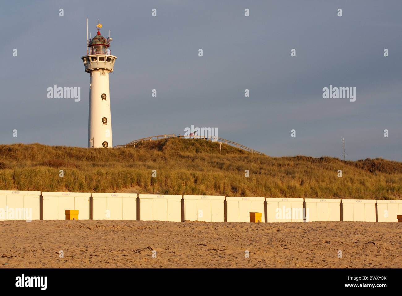 Vue de la plage à J.C.J. van Speyk phare avec cabines de plage à l'avant dans le chaud soleil du soir Banque D'Images