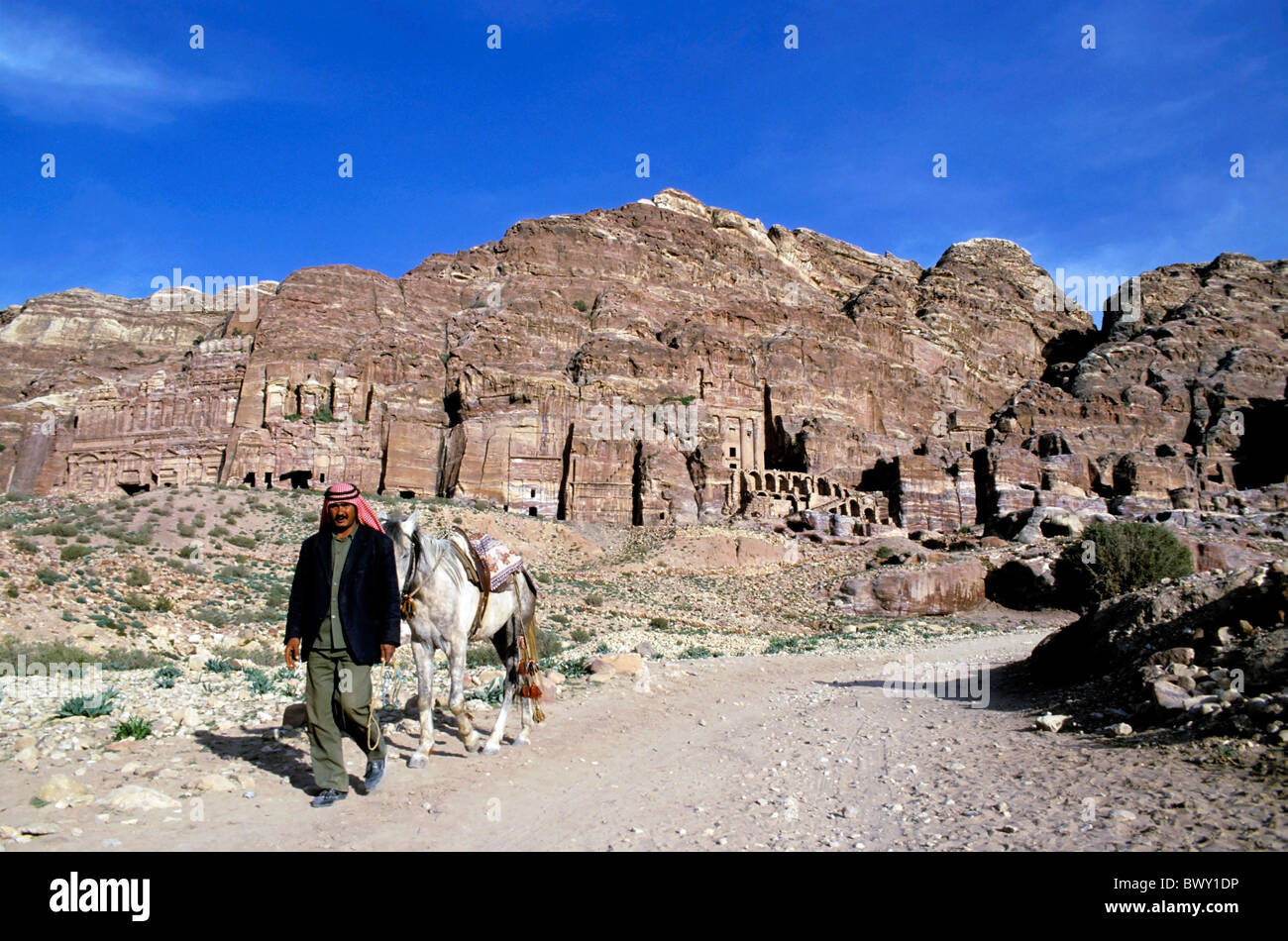 Petra, JORDANIE - homme marchant avec son cheval près de l'entrée du Royal Tombs creusé dans les falaises à Pétra Banque D'Images