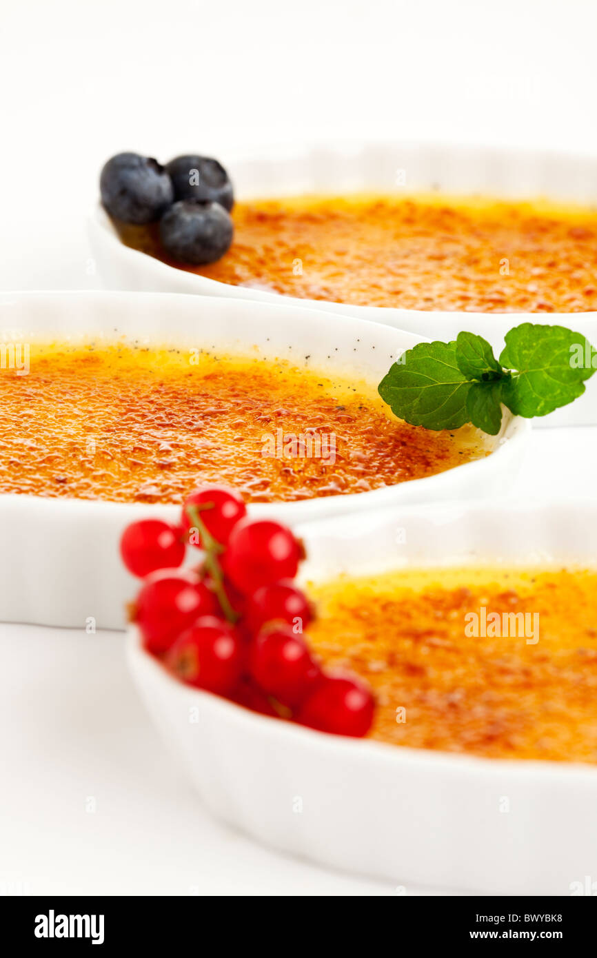 Trois bols de cuisine française dessert crème brûlée garnie avec les bleuets, les feuilles de menthe, groseille, selective focus Banque D'Images