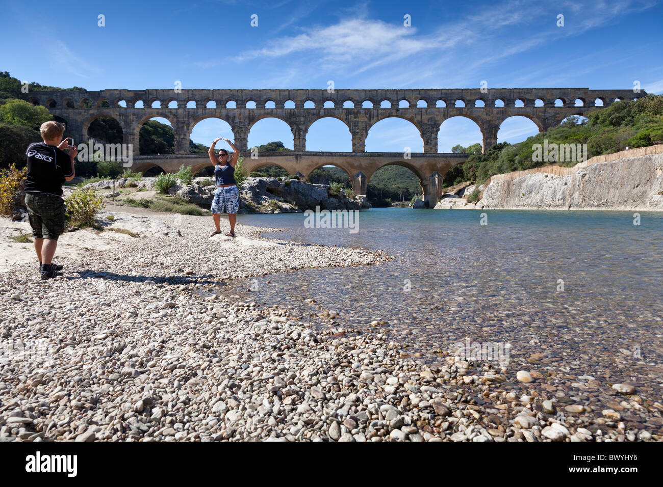 Un touristes posent devant le Pont du Gard, Gard, Languedoc-Roussillon, France. Banque D'Images