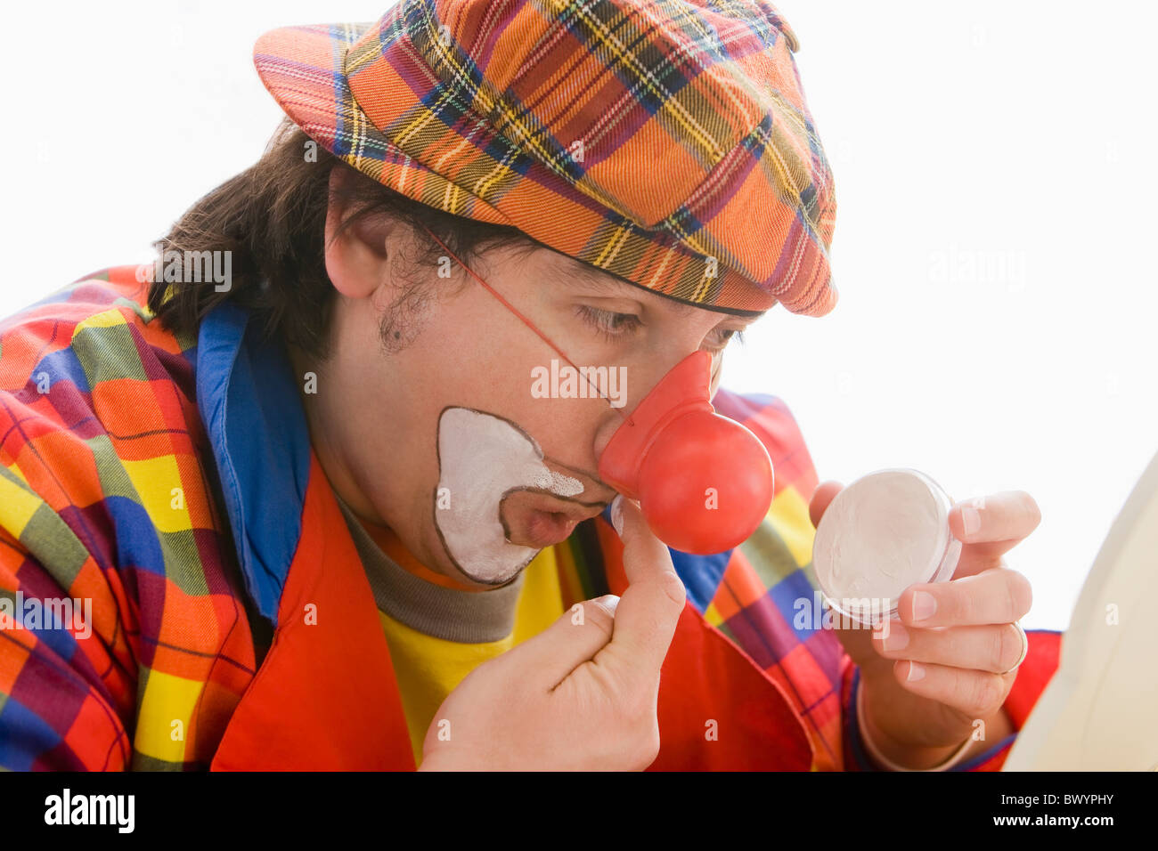 Hispanic man putting sur le maquillage de clown Banque D'Images