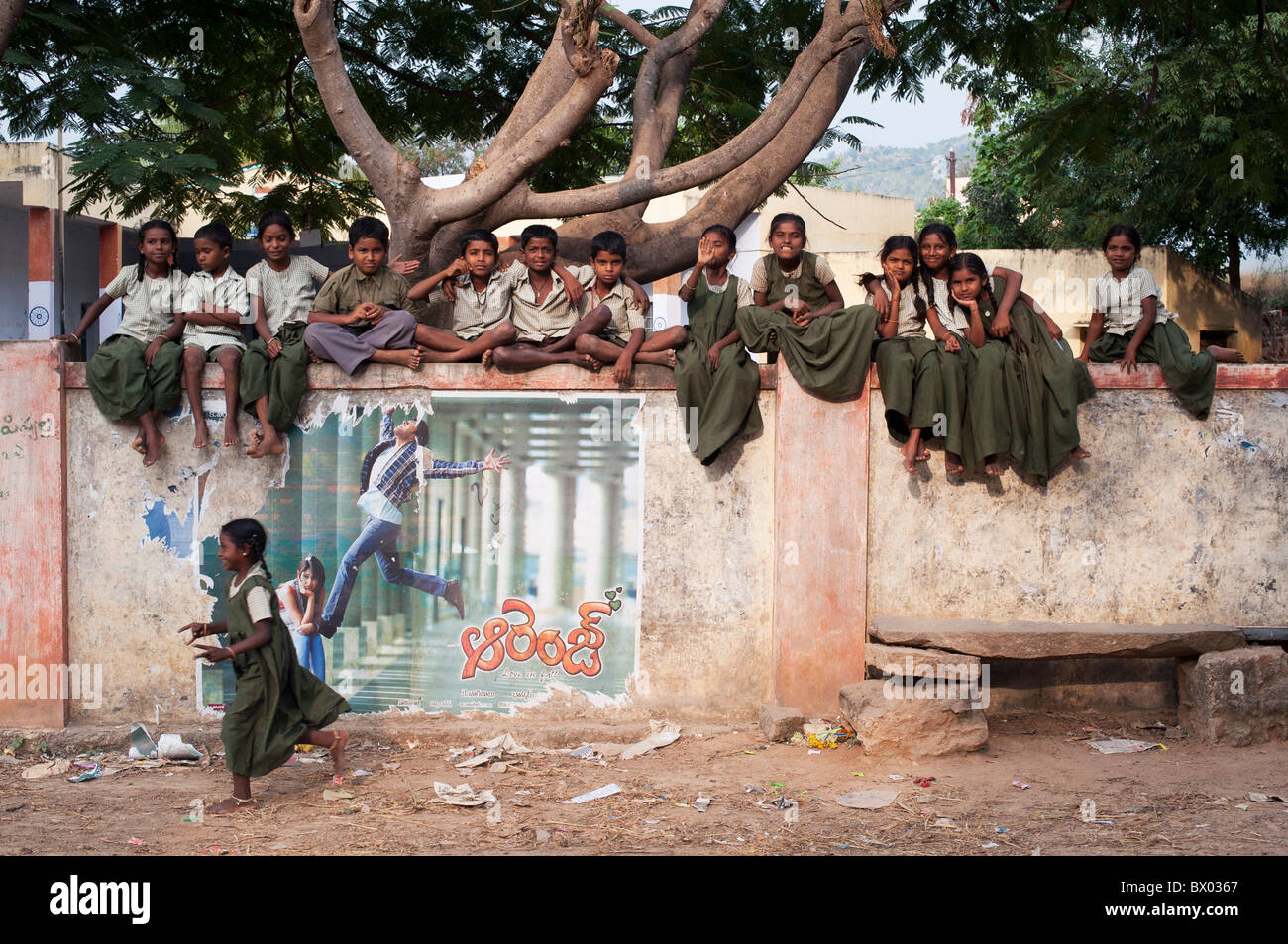 Les enfants de l'école village assis sur leur mur d'école. L'Andhra Pradesh, Inde Banque D'Images