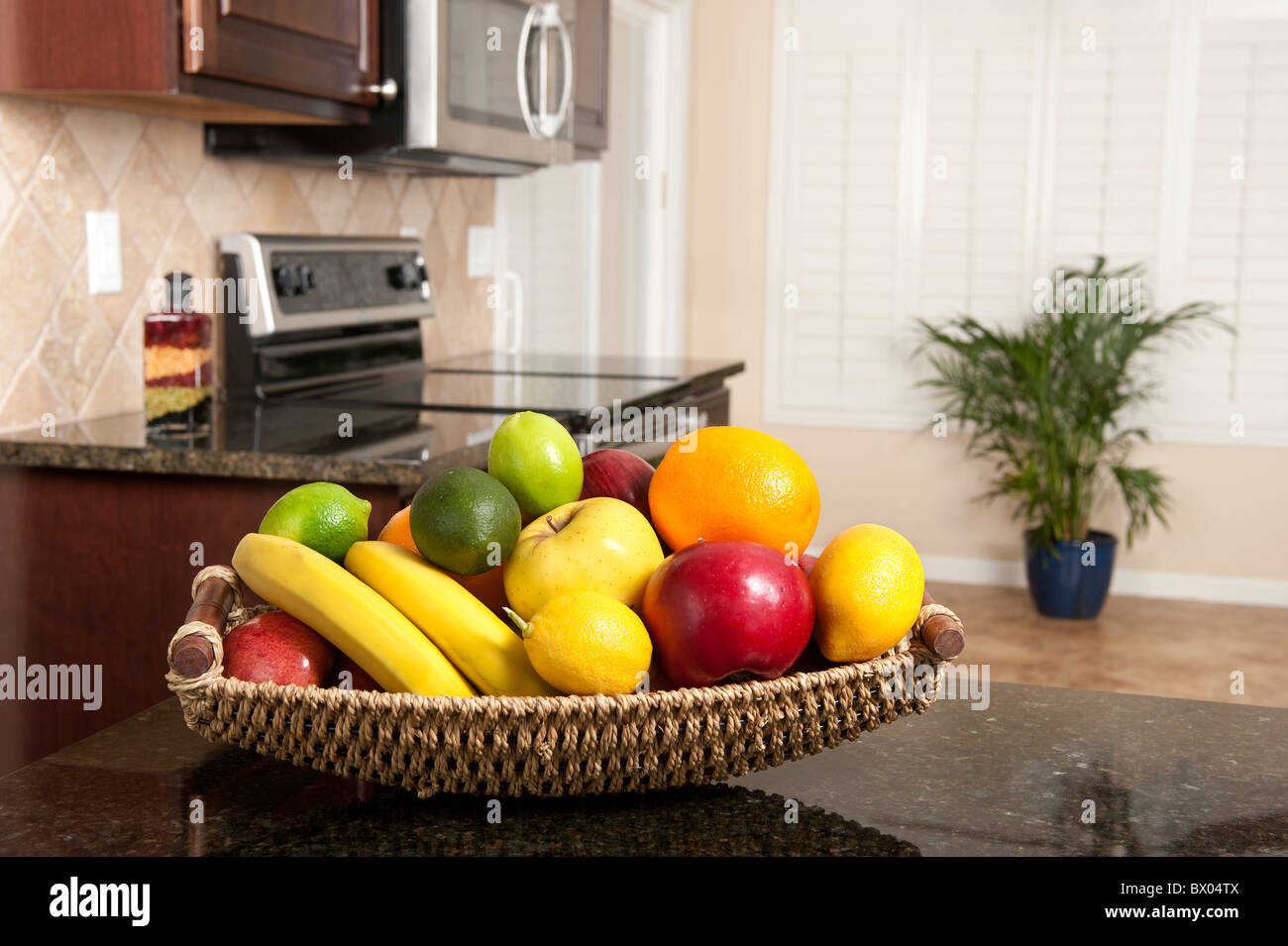 Une corbeille de fruits frais sur un comptoir de granit dans une cuisine récemment rénovée. Banque D'Images