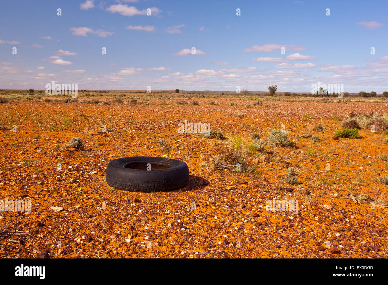 Des pneus de véhicule à moteur dans un paysage rouge vide baragouinent entre Broken Hill et Menindee en Nouvelle Galles du Sud Banque D'Images
