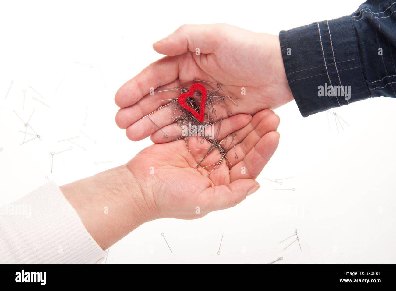 Deux mains, le coeur et les aiguilles symbolisant les relations en crise Banque D'Images