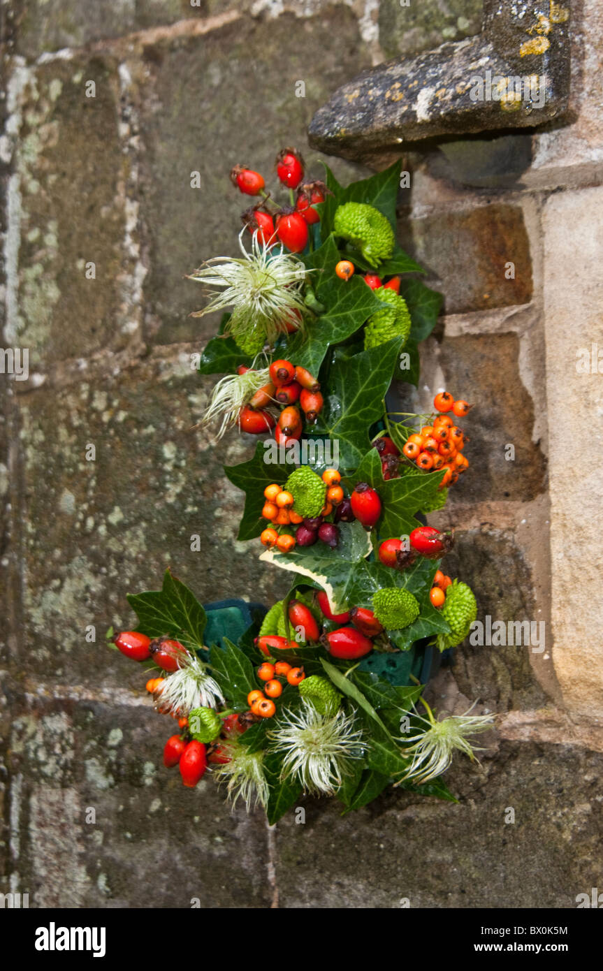 Une décoration florale y compris les petits fruits rouges et orange sur une église de pierre Banque D'Images