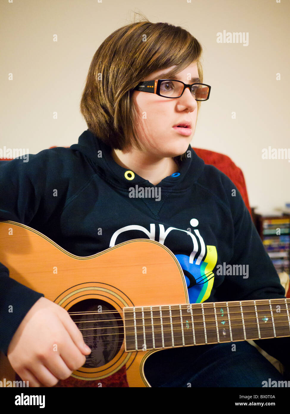 Une jeune fille portant des lunettes jouer a 12 cordes guitare acoustique. Banque D'Images