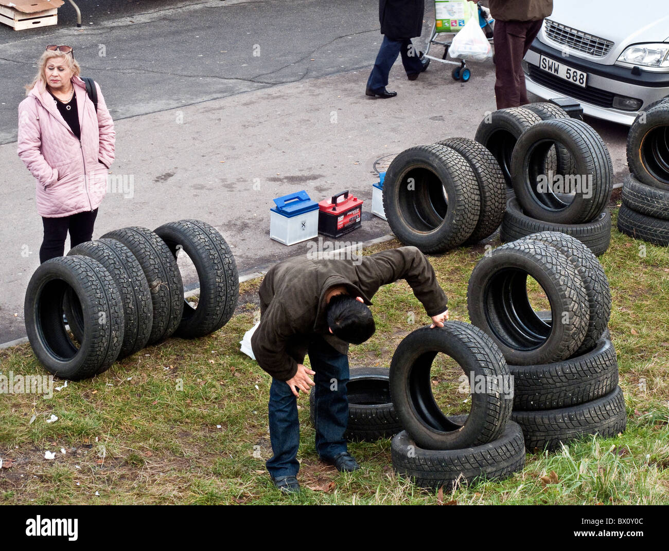 Un homme examine attentivement les pneus d'occasion affichée à week-end bondé marché aux puces en périphérie de Göteborg, Suède. Banque D'Images