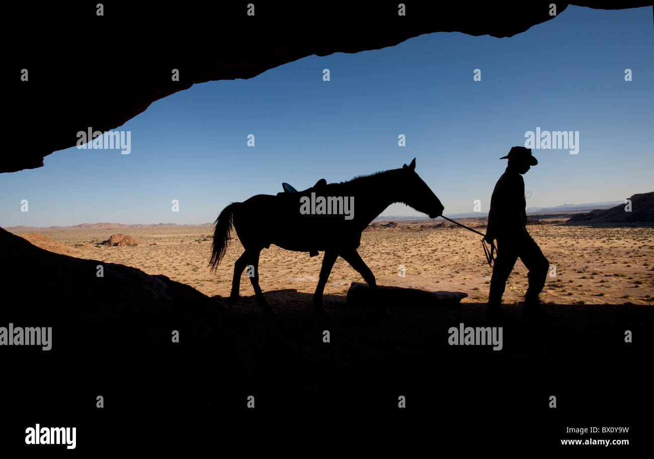 Silhouette d'un homme conduisant son cheval le long d'une crête, Fish River Canyon, la Namibie, l'Afrique. Banque D'Images