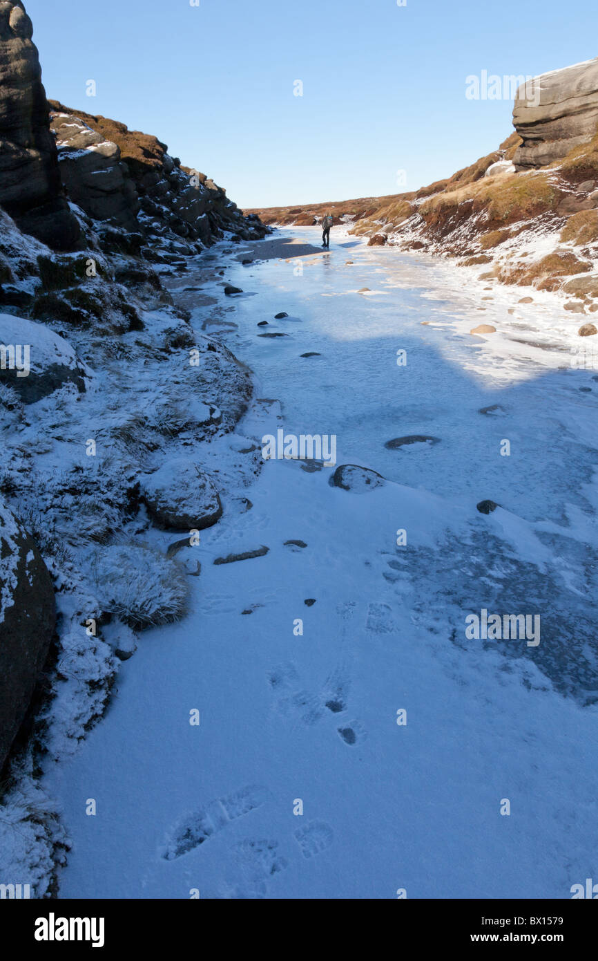 Un marcheur sur la rivière gelée, hiver sur Kinder Kinder Scout dans l'Obscurité crête du parc national de Peak District, Derbyshire Banque D'Images