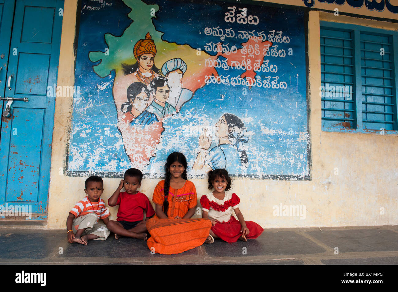 Les enfants indiens assis en face d'une carte colorée de l'inde la peinture sur un bâtiment indien, de l'Andhra Pradesh, Inde Banque D'Images