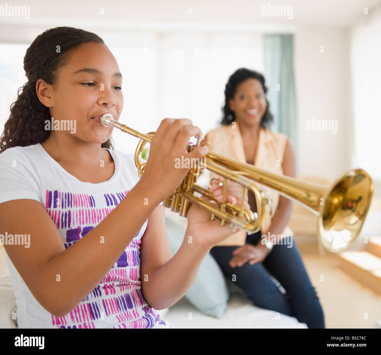 Mère regardant fille playing trumpet Banque D'Images