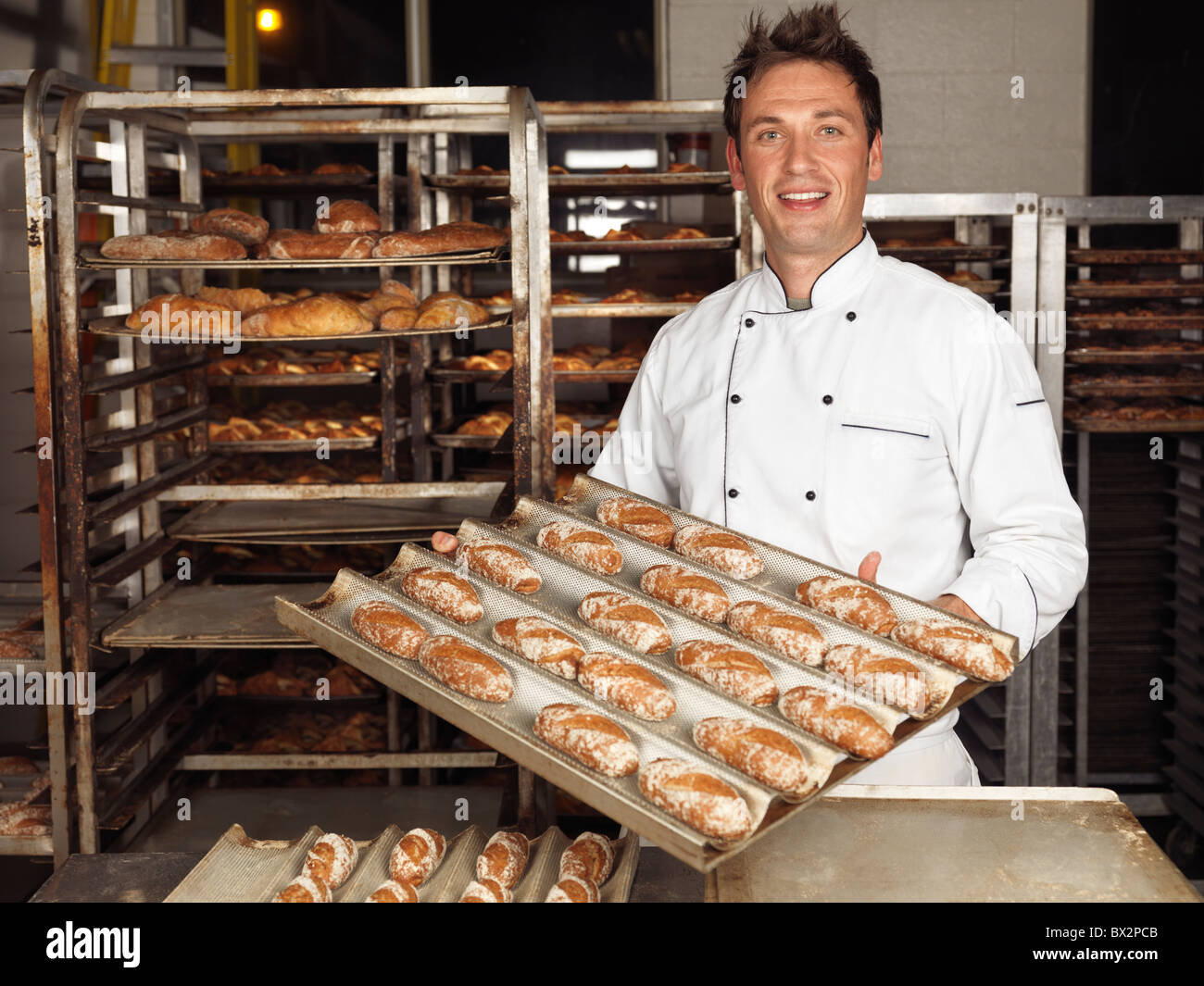 Portrait of a baker tenant un plateau avec des petits pains fraîchement cuits dans une boulangerie Banque D'Images