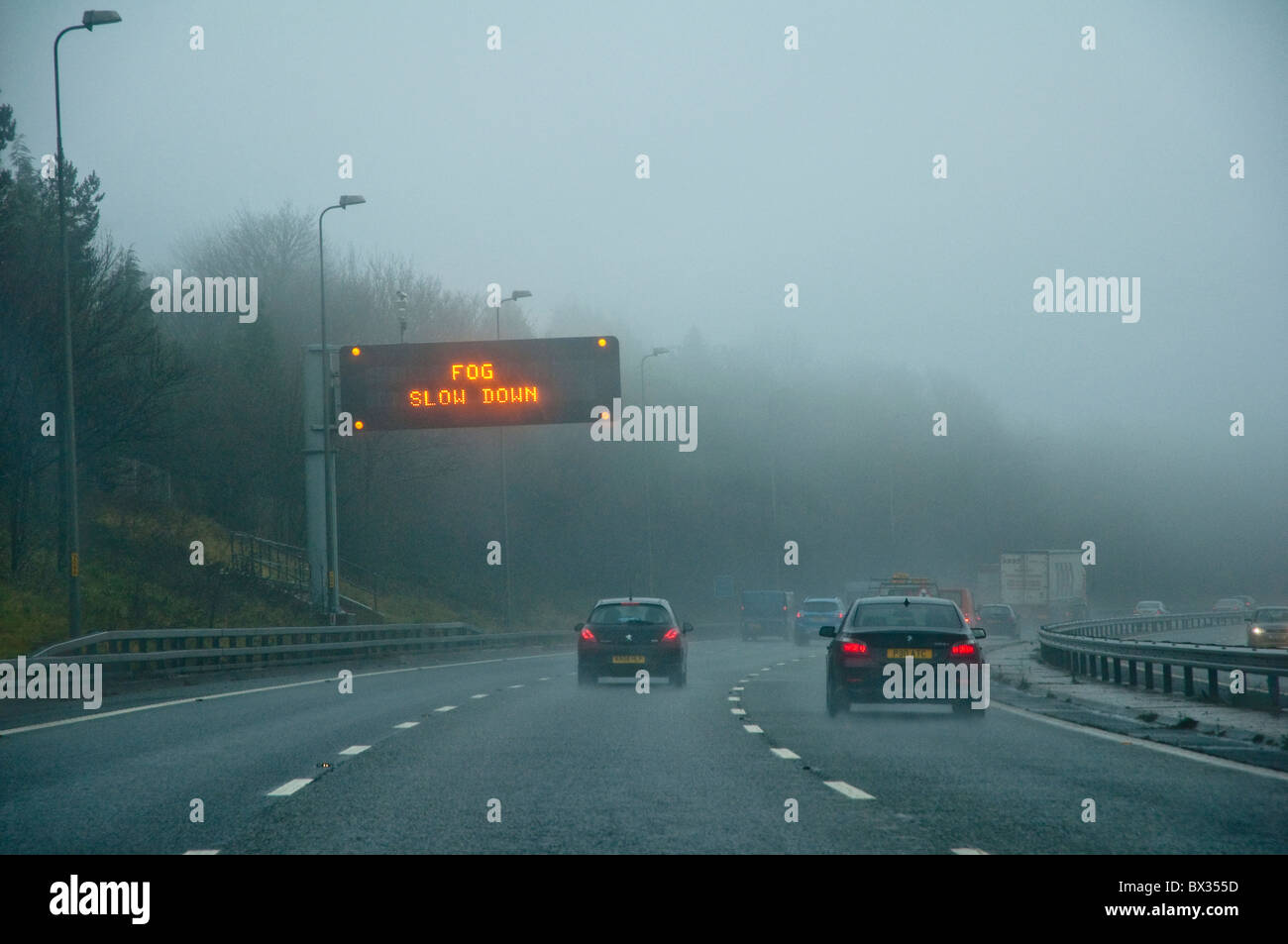 Brouillard 'Ralentir' - l'autoroute panneau d'avertissement. Point de vue des pilotes avec des voitures et la mauvaise visibilité. M5, au Royaume-Uni. Banque D'Images