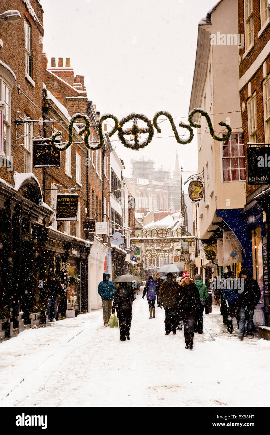 Les gens portant des vêtements chauds d'hiver marchant le long de Stonegate dans la neige. York. Banque D'Images