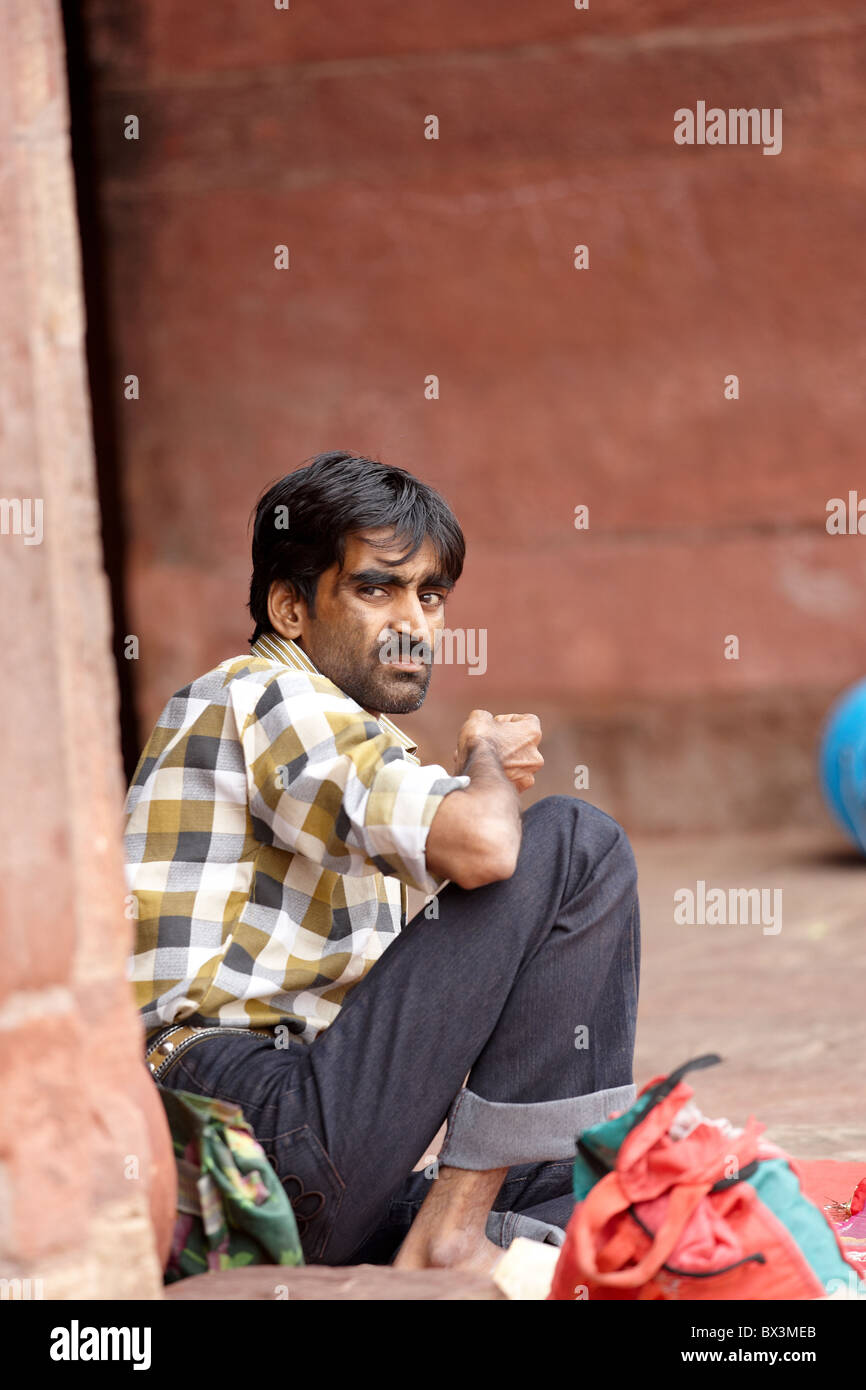 Indian homme accroupi avec revêche sur le visage Banque D'Images