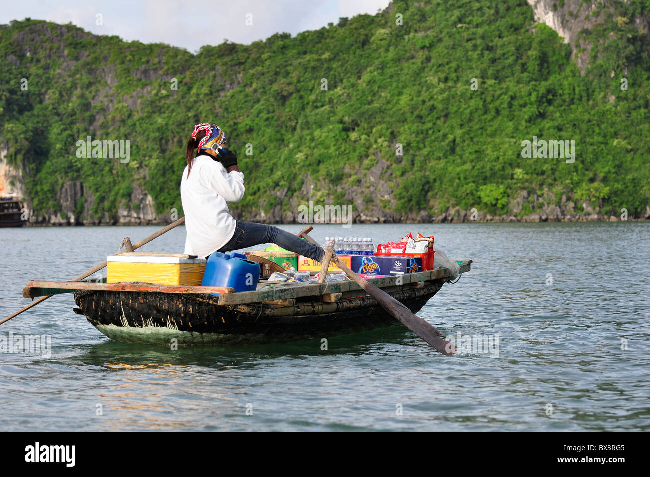 Femme non identifiée parle dans son portable tandis que son bateau d'aviron. La couverture mobile est évidemment bon aussi loin de la terre. Banque D'Images