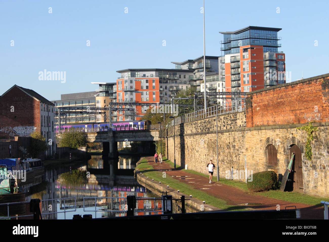 Afficher le long de Leeds et Liverpool canal dans le centre-ville de Leeds avec train sur pont de chemin de fer près de la gare de Leeds. Banque D'Images