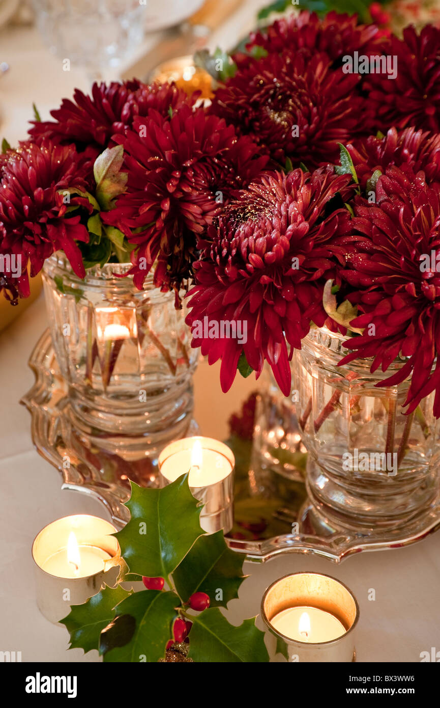 Décoration de table de Noël de bougies en ronds de serviette marron avec des chrysanthèmes. Banque D'Images