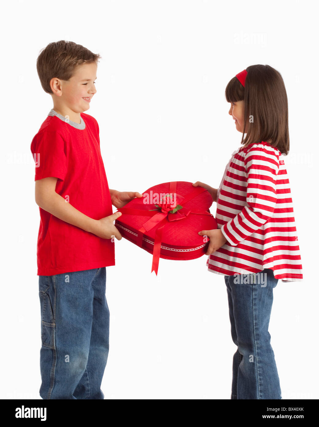 Un garçon donne une boîte en forme de coeur pour une fille Banque D'Images