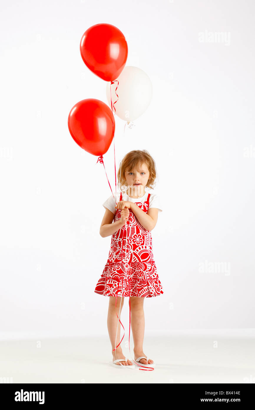 Une fille tenant deux ballons rouges Banque D'Images