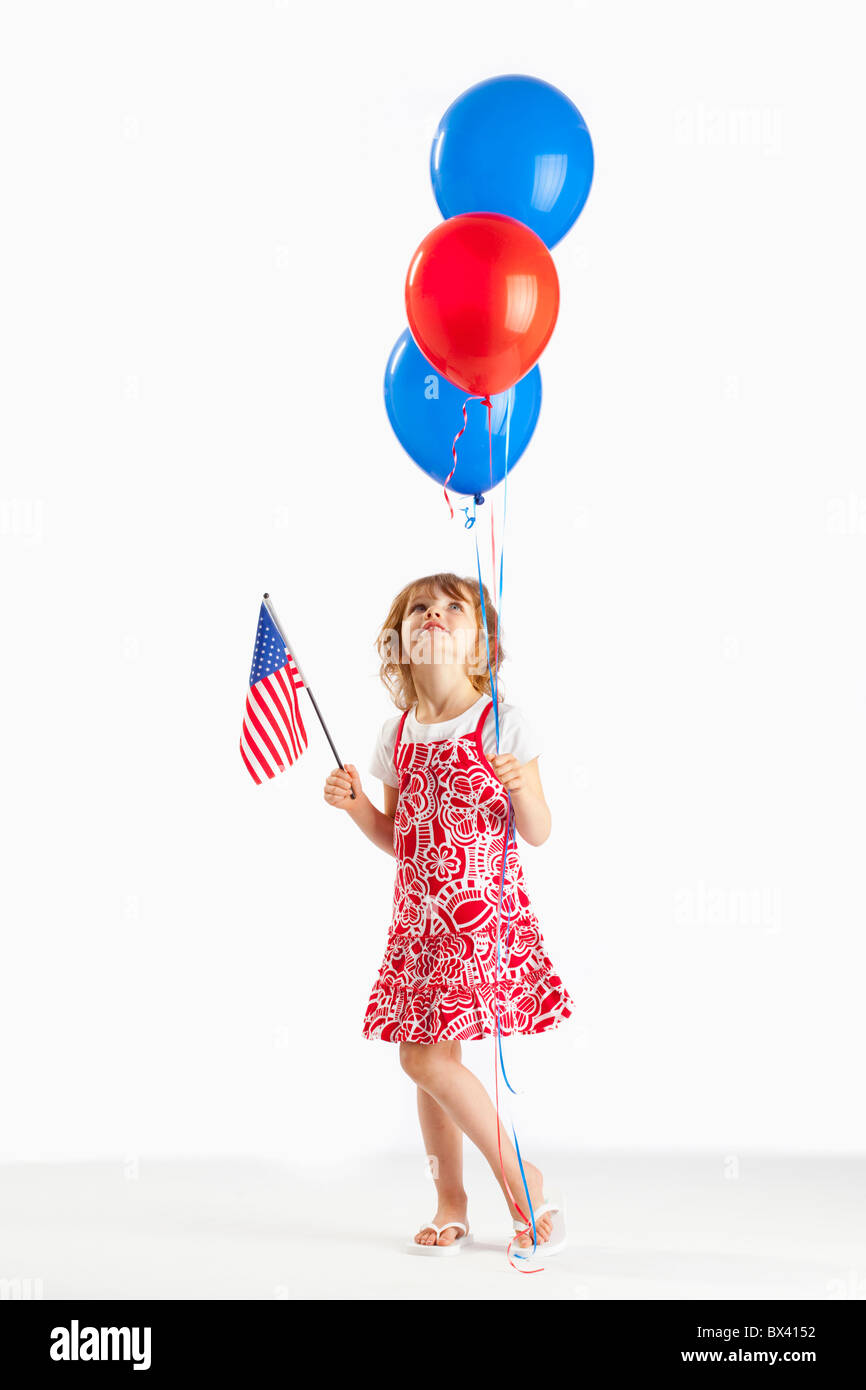 Une fille tenant des ballons rouges et bleus et un drapeau américain Banque D'Images