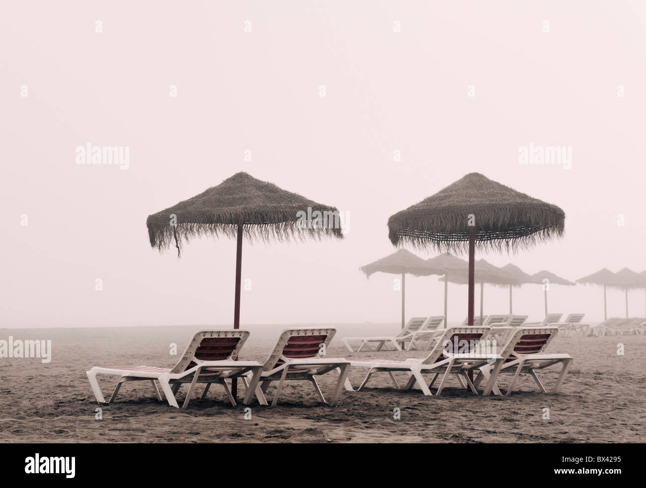 Chaises longues et parasol sur la plage Playamar en hors saison en un jour brumeux, Torremolinos, Malaga, Costa del Sol, Espagne Banque D'Images