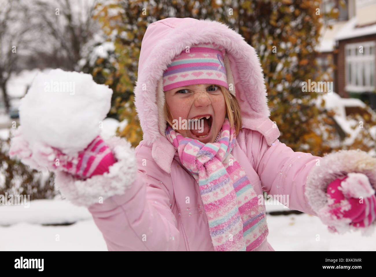Une jeune fille espiègle prêt à jeter une boule de neige Banque D'Images
