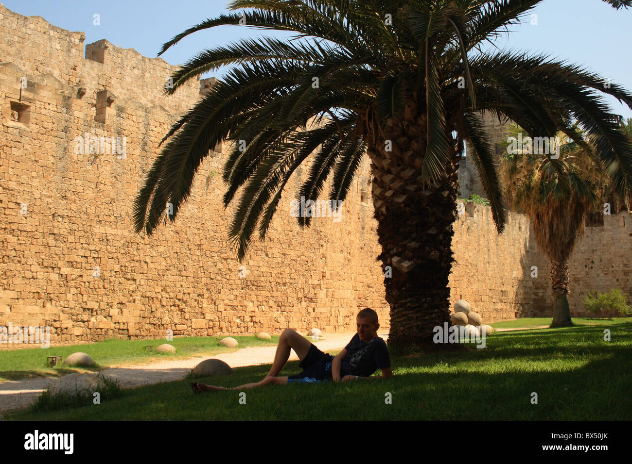 Jeune homme sous l'arbre à l'ancien château sur Rhodes Banque D'Images