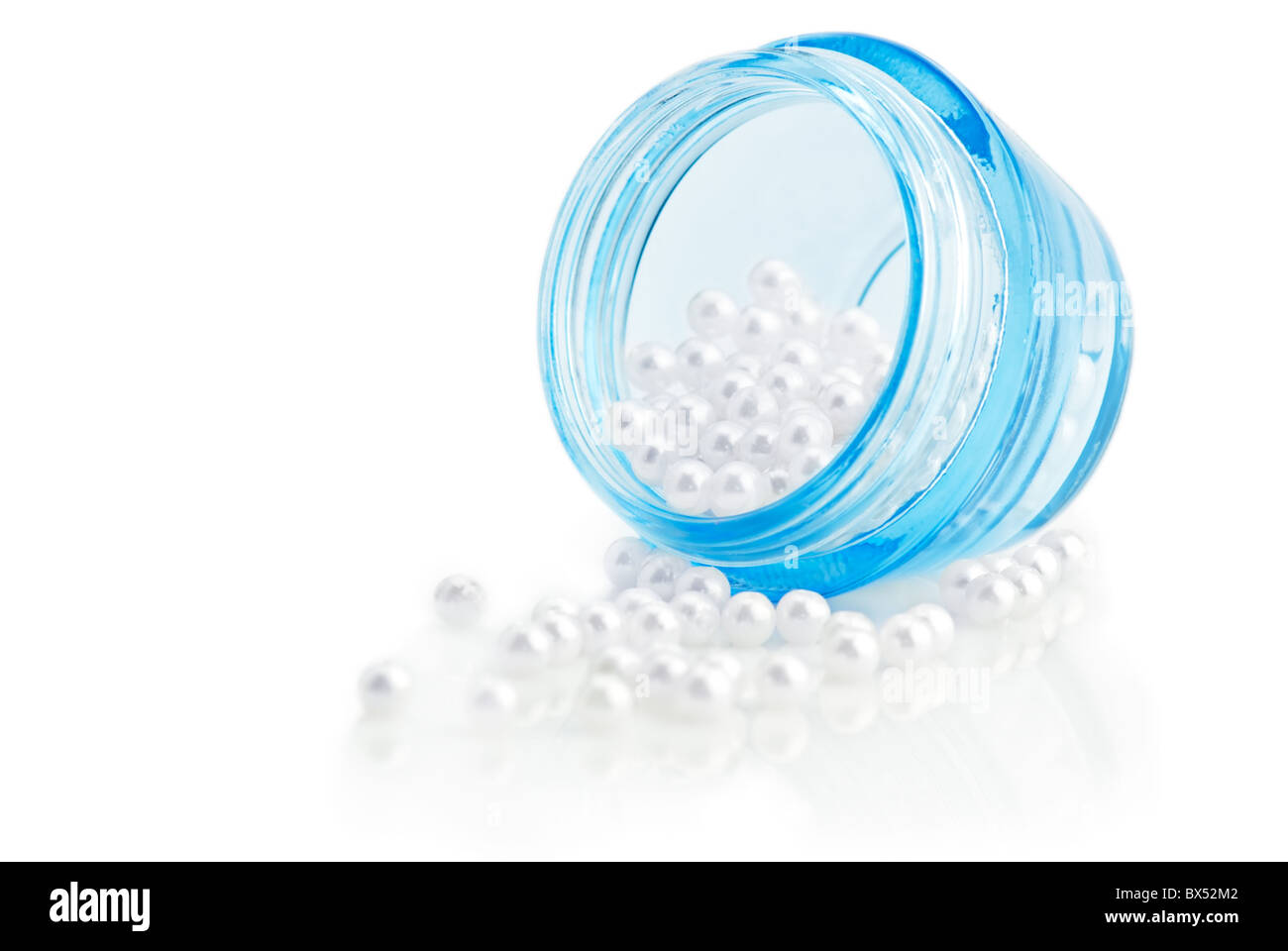 Concept de beauté. Cosmetic récipient plein de perles naturelles sur fond blanc. Profondeur de champ Banque D'Images