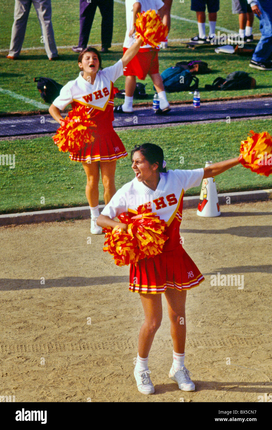 Cheerleaders agitent leurs pompons à un match de football de l'école dans le sud de la Californie. Banque D'Images