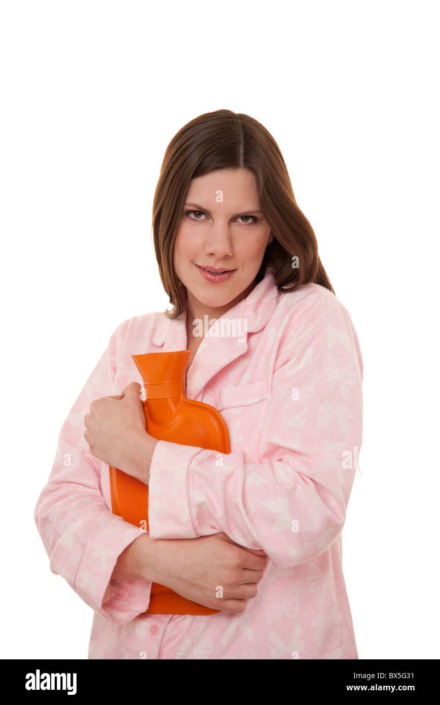 Femme tenant une bouteille d'eau chaude vêtue de son pyjama. Banque D'Images