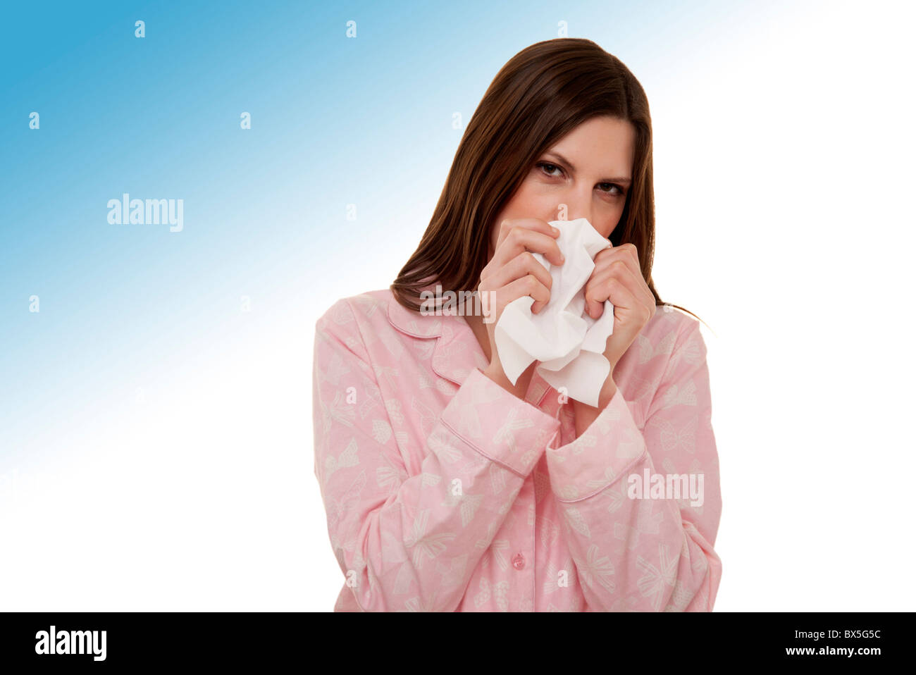 Woman blowing son nez wearing pajamas Banque D'Images